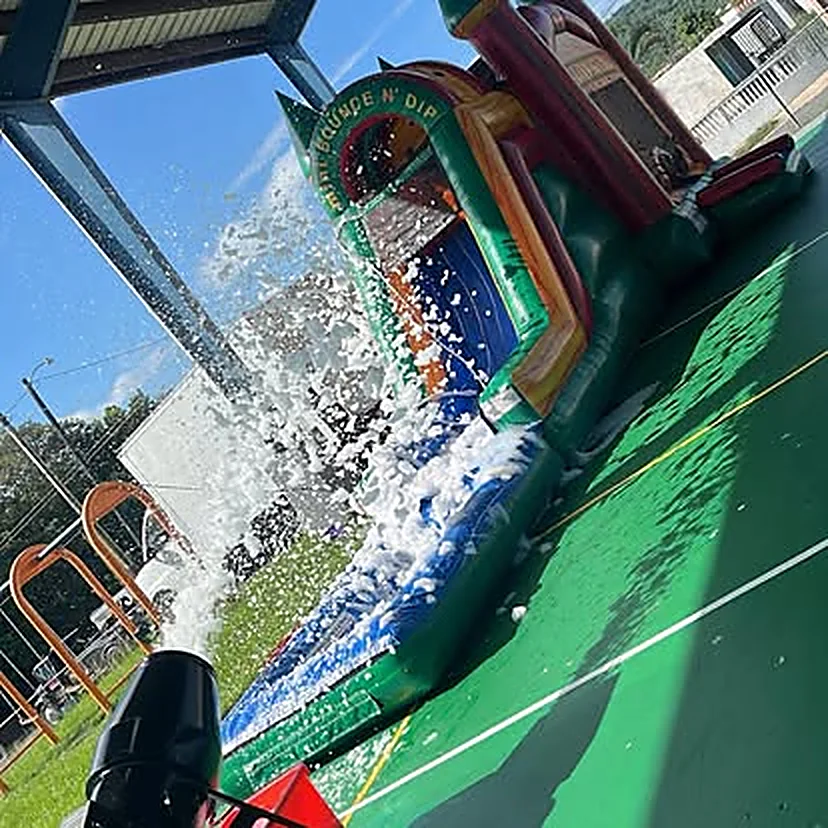 Una chorrera de agua de Brincando y Algo Más en pleno uso, con el agua y la espuma bajando por la rampa